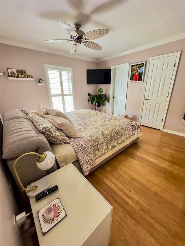 bedroom featuring ceiling fan, crown molding, baseboards, and wood finished floors