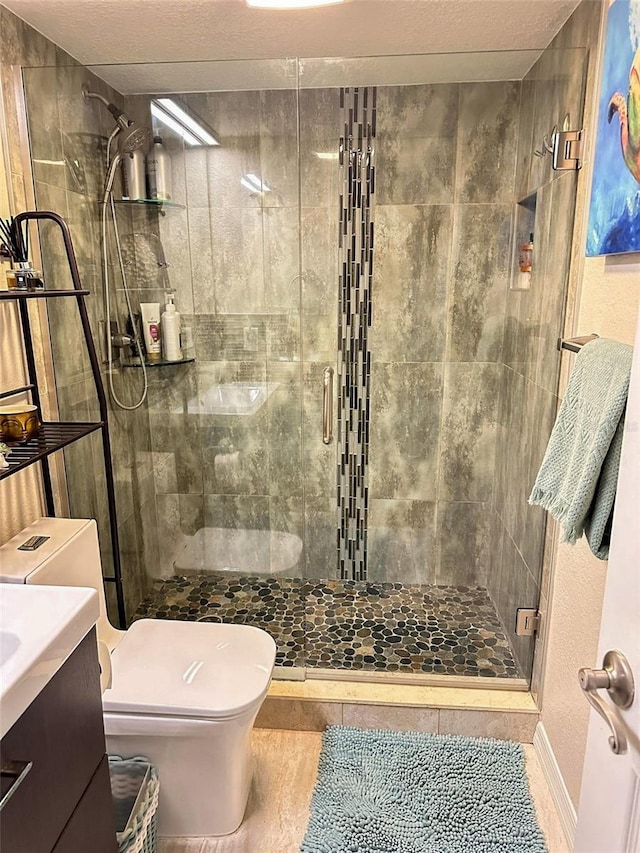 bathroom featuring a textured ceiling, a stall shower, vanity, and toilet