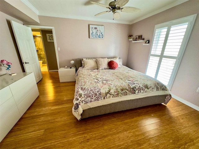 bedroom featuring baseboards, multiple windows, ornamental molding, and wood finished floors