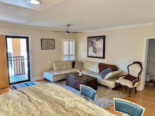 living room with baseboards, ceiling fan, ornamental molding, wood finished floors, and a textured ceiling