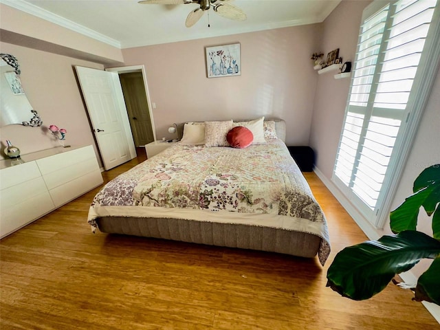 bedroom with light wood-type flooring, ceiling fan, and crown molding