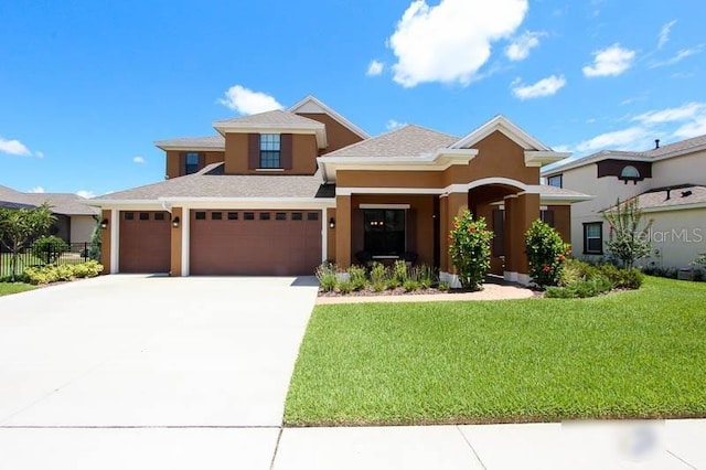 prairie-style house featuring fence, concrete driveway, a front yard, stucco siding, and an attached garage