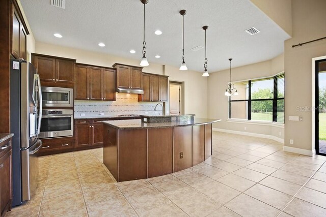 kitchen featuring visible vents, under cabinet range hood, backsplash, stainless steel appliances, and light tile patterned floors