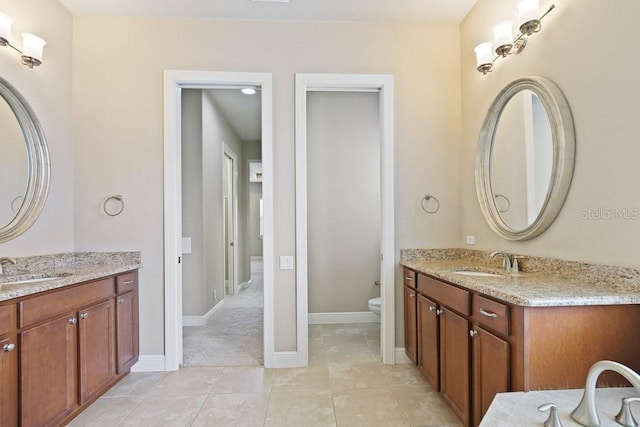 bathroom with tile patterned floors, toilet, two vanities, and a sink