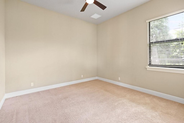 spare room featuring a ceiling fan, light colored carpet, and baseboards