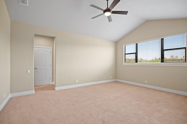 empty room featuring visible vents, baseboards, ceiling fan, lofted ceiling, and light carpet