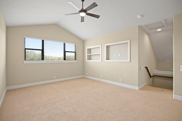 empty room featuring vaulted ceiling, attic access, built in features, and carpet