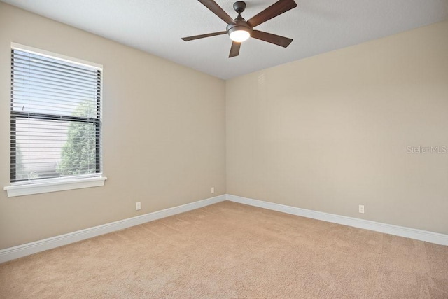 empty room with a ceiling fan, light colored carpet, and baseboards