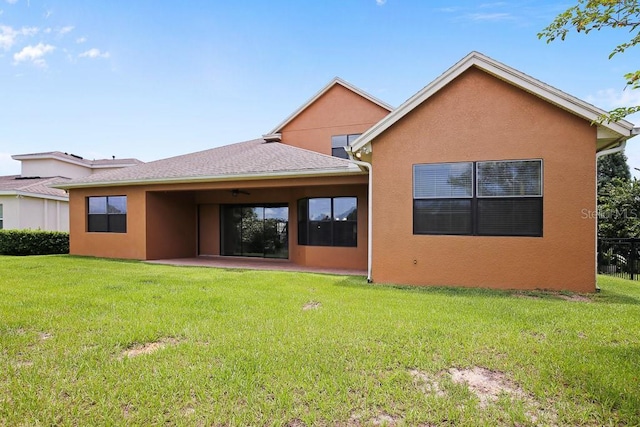 rear view of house with a lawn, a patio, and stucco siding