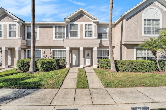 multi unit property featuring a front lawn and stucco siding