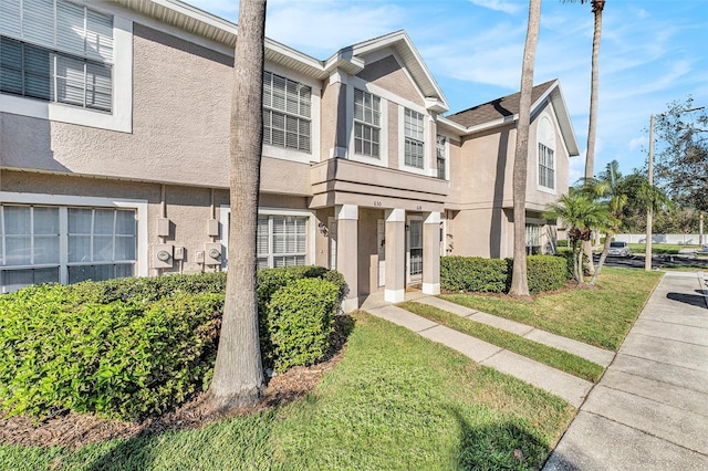 townhome / multi-family property featuring a front lawn and stucco siding