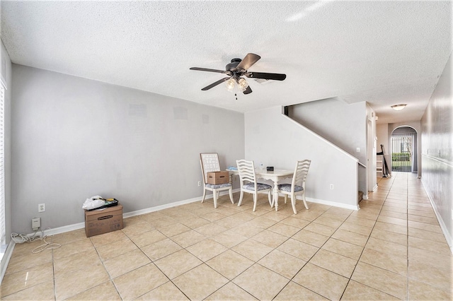 dining room featuring arched walkways, ceiling fan, a textured ceiling, and light tile patterned flooring