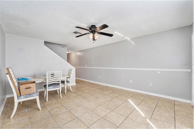 dining space with light tile patterned floors, a textured ceiling, visible vents, a ceiling fan, and baseboards