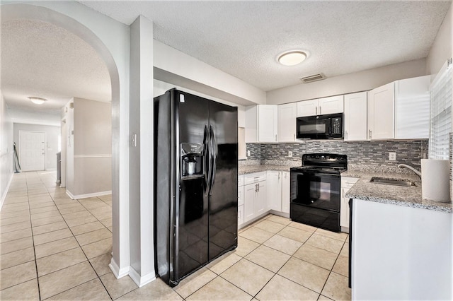 kitchen with light tile patterned floors, visible vents, white cabinets, light stone countertops, and black appliances