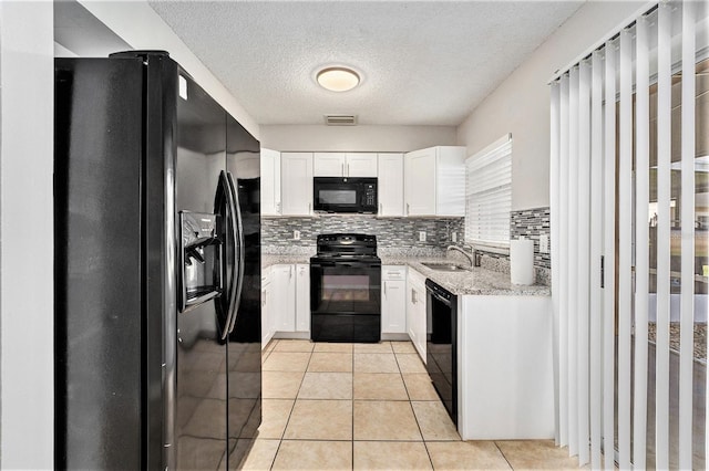 kitchen with visible vents, light stone countertops, black appliances, white cabinetry, and a sink