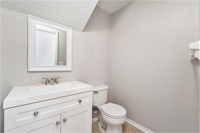 half bathroom featuring a textured ceiling, tile patterned flooring, toilet, vanity, and baseboards