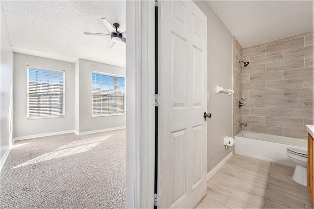 full bathroom with toilet, a ceiling fan, vanity, shower / tub combination, and a textured ceiling