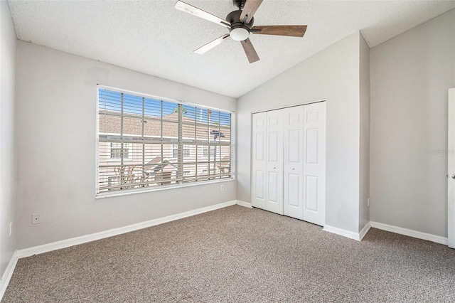 unfurnished bedroom featuring carpet, lofted ceiling, a closet, a textured ceiling, and baseboards