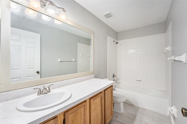 bathroom with visible vents, shower / bathtub combination, vanity, and toilet