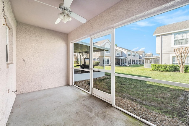 unfurnished sunroom with a residential view and ceiling fan