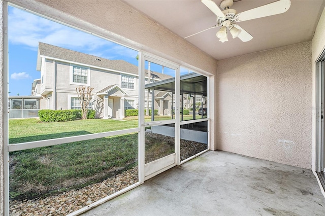 unfurnished sunroom featuring a residential view and a ceiling fan