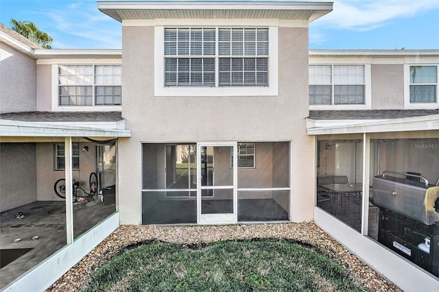 rear view of property featuring a sunroom and stucco siding