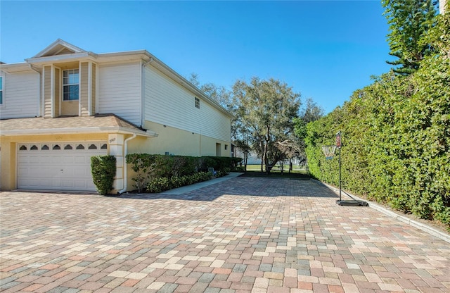 view of side of property with decorative driveway and an attached garage