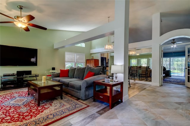 living room with baseboards, a high ceiling, and ceiling fan with notable chandelier