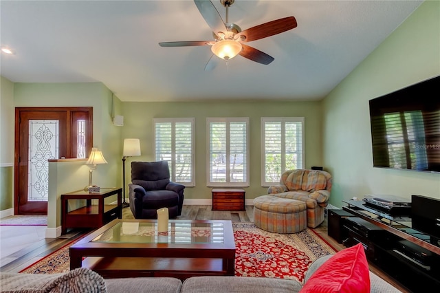 living area with ceiling fan, baseboards, vaulted ceiling, and wood finished floors