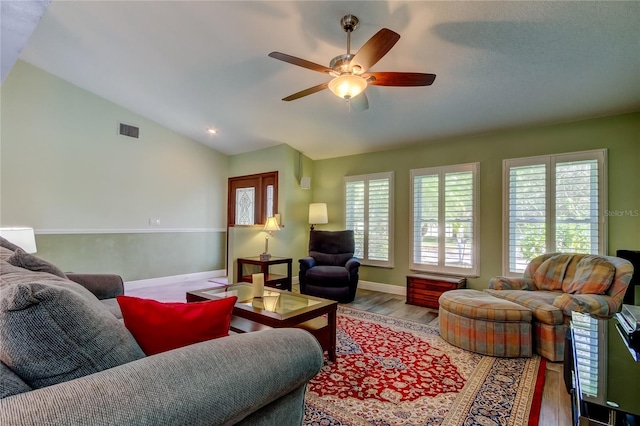 living room featuring baseboards, visible vents, a ceiling fan, wood finished floors, and vaulted ceiling