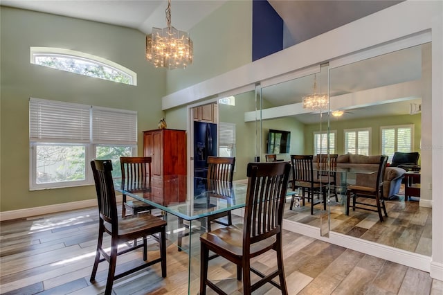 dining space featuring high vaulted ceiling, light wood-type flooring, plenty of natural light, and baseboards