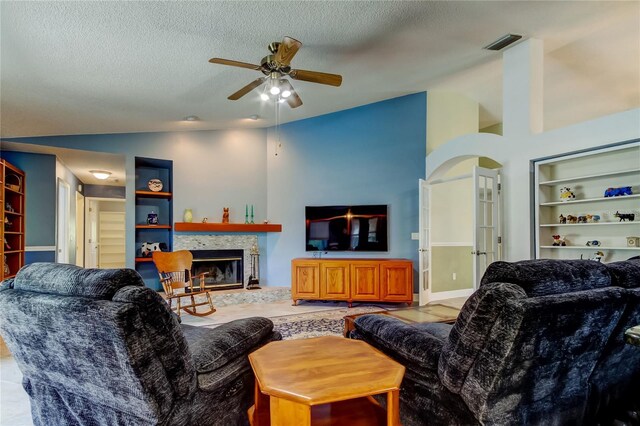 living area with visible vents, arched walkways, a glass covered fireplace, lofted ceiling, and a textured ceiling