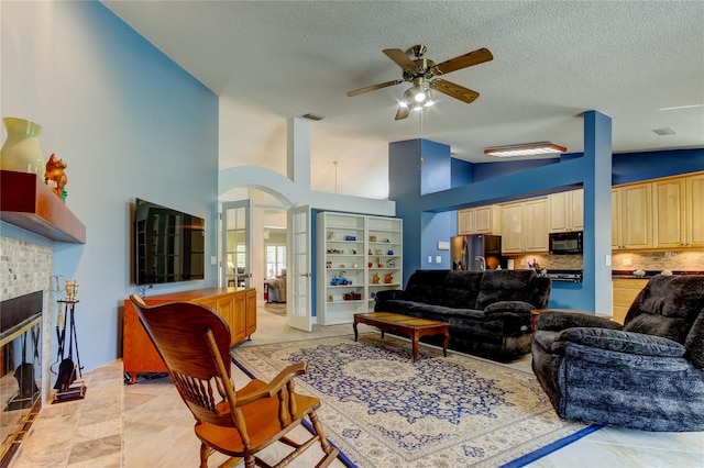 living room featuring visible vents, a brick fireplace, ceiling fan, a textured ceiling, and high vaulted ceiling