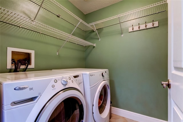 laundry area with laundry area, washing machine and dryer, baseboards, and a textured ceiling