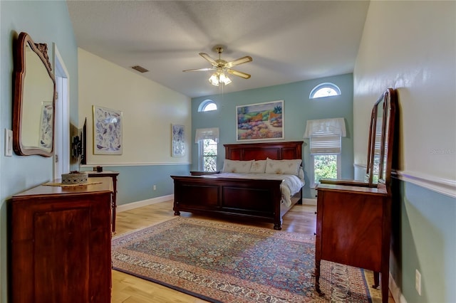 bedroom featuring ceiling fan, light wood-style flooring, visible vents, and baseboards