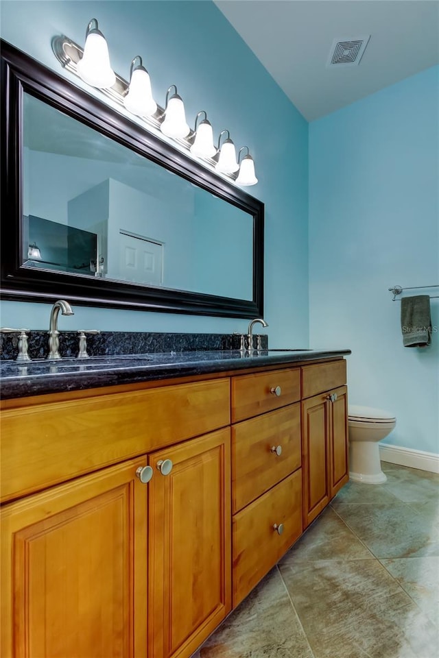 full bath featuring toilet, double vanity, visible vents, and a sink