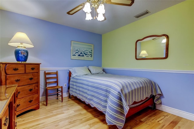 bedroom featuring a ceiling fan, baseboards, visible vents, and wood finished floors