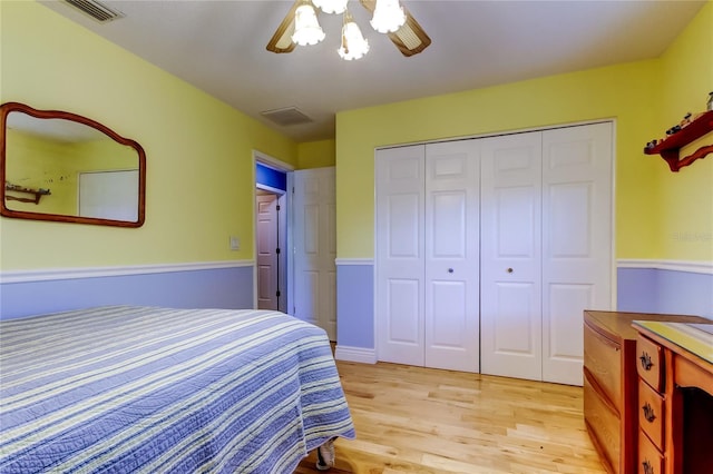 bedroom with light wood-style floors, a ceiling fan, visible vents, and a closet