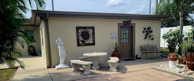 property entrance featuring a patio, fence, and stucco siding