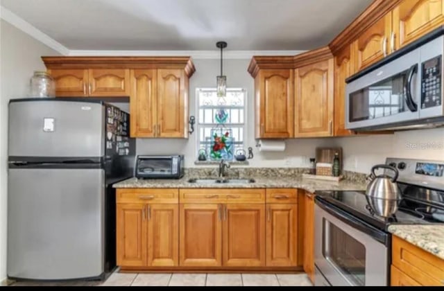 kitchen featuring light stone counters, appliances with stainless steel finishes, brown cabinets, and a sink