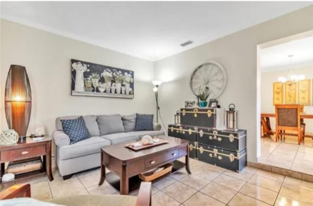 living area with light tile patterned flooring, visible vents, and an inviting chandelier