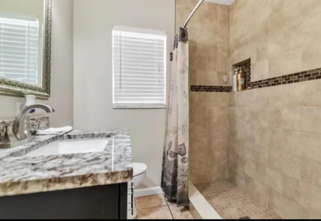 bathroom featuring toilet, a tile shower, vanity, and tile patterned floors