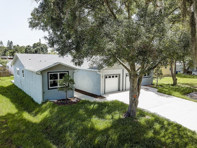 view of front of home with a garage, concrete driveway, a front yard, and stucco siding