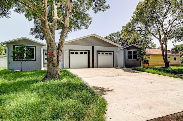 single story home featuring a garage, a front yard, concrete driveway, and stucco siding