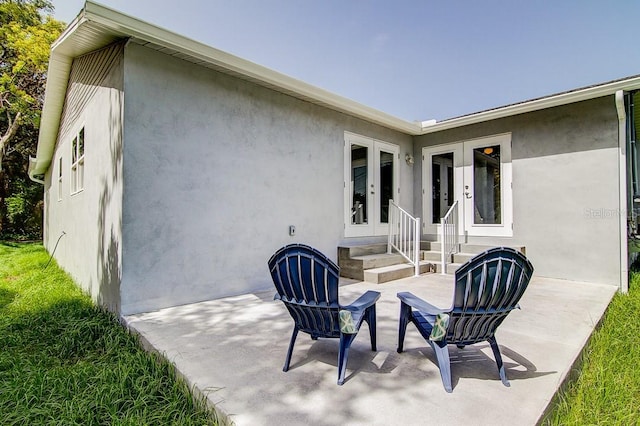 rear view of house featuring entry steps, french doors, a patio area, and stucco siding