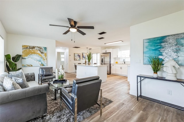 living area with light wood-style floors and ceiling fan