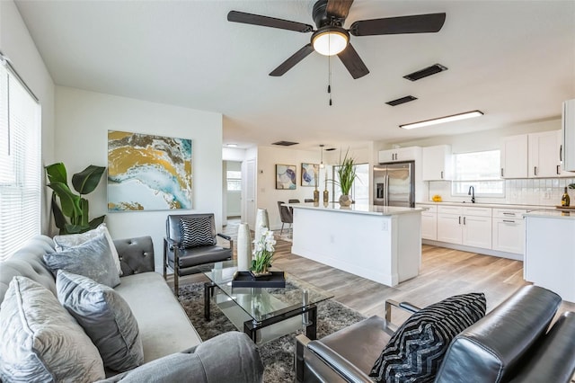 living area with light wood-style floors, visible vents, and a ceiling fan