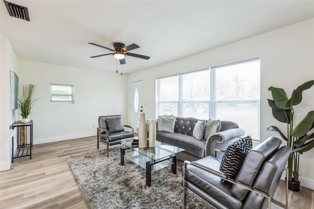 living area featuring a ceiling fan, light wood-type flooring, visible vents, and baseboards