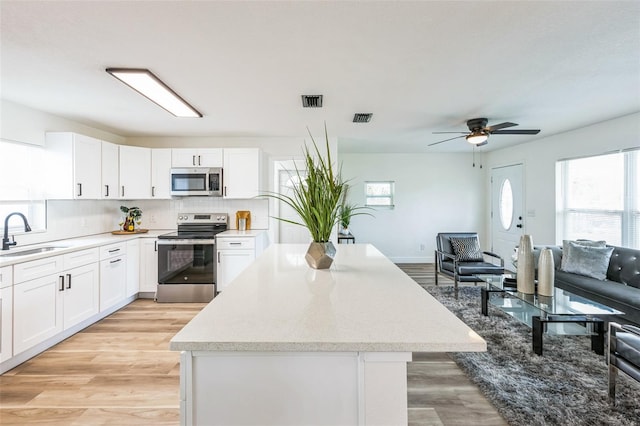 kitchen featuring visible vents, white cabinetry, stainless steel appliances, and a sink