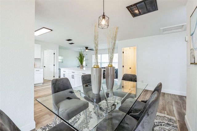 dining space featuring visible vents, a ceiling fan, baseboards, light wood finished floors, and attic access